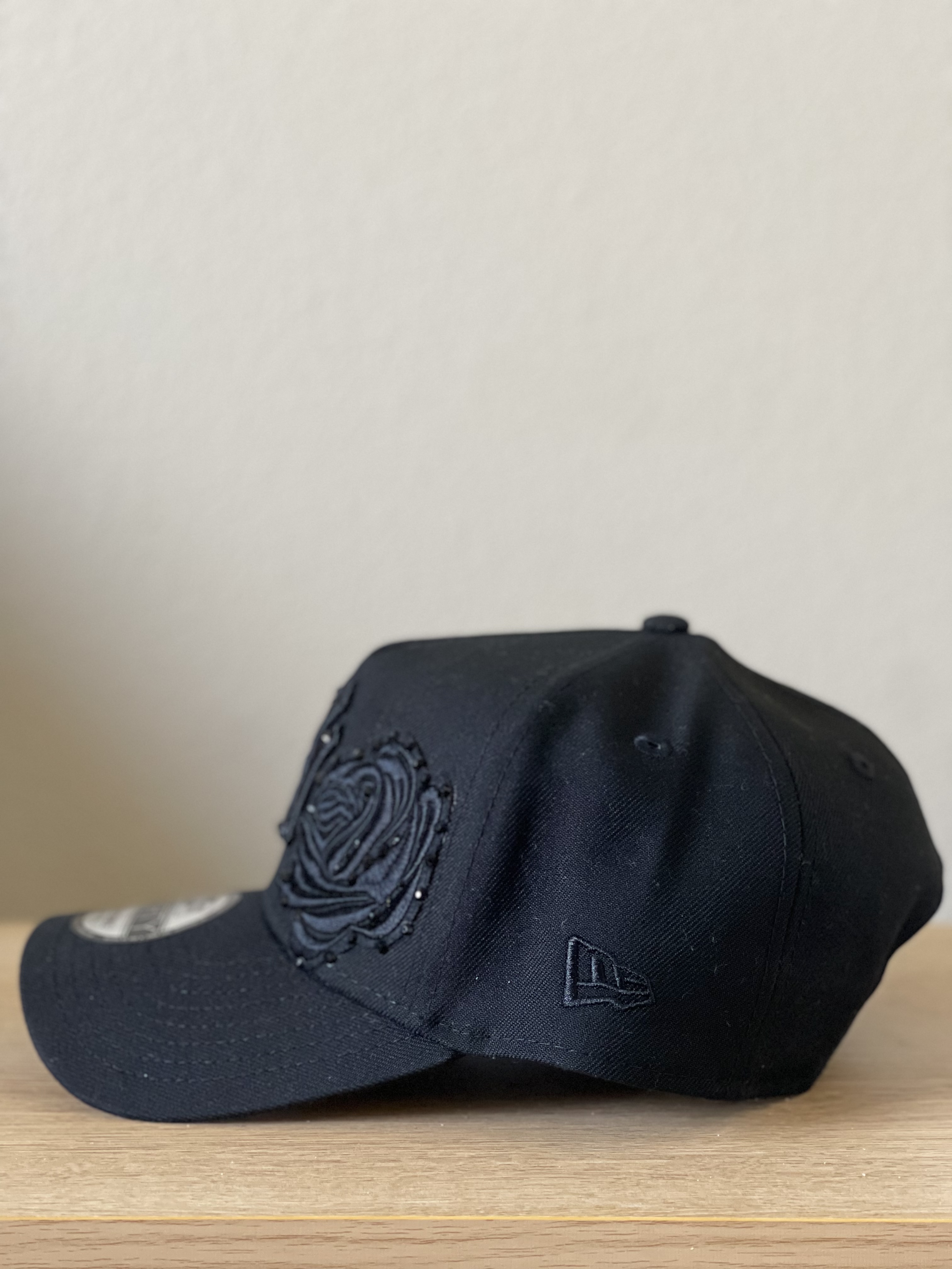 Black Yankees snapback with tonal black rose applique, side profile.