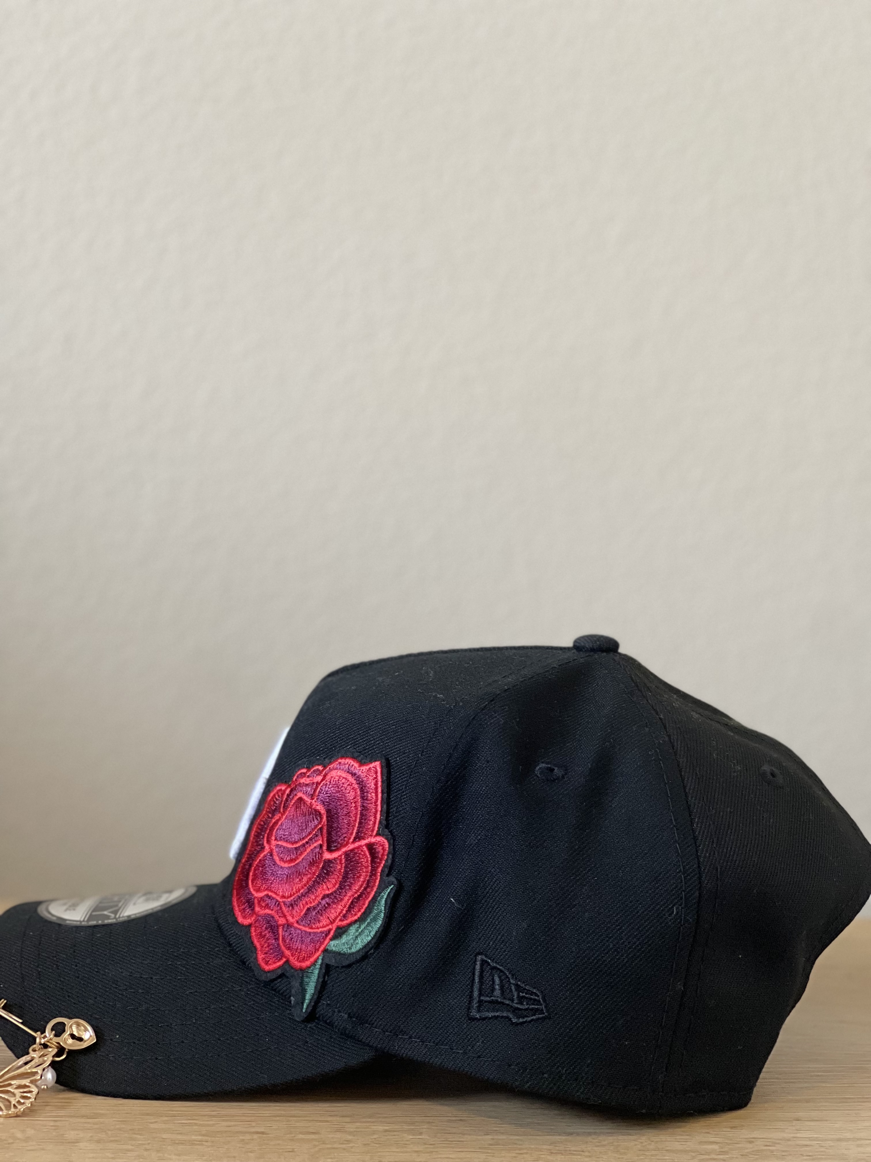 Black LA snapback with rose applique and charm detail, side angle.