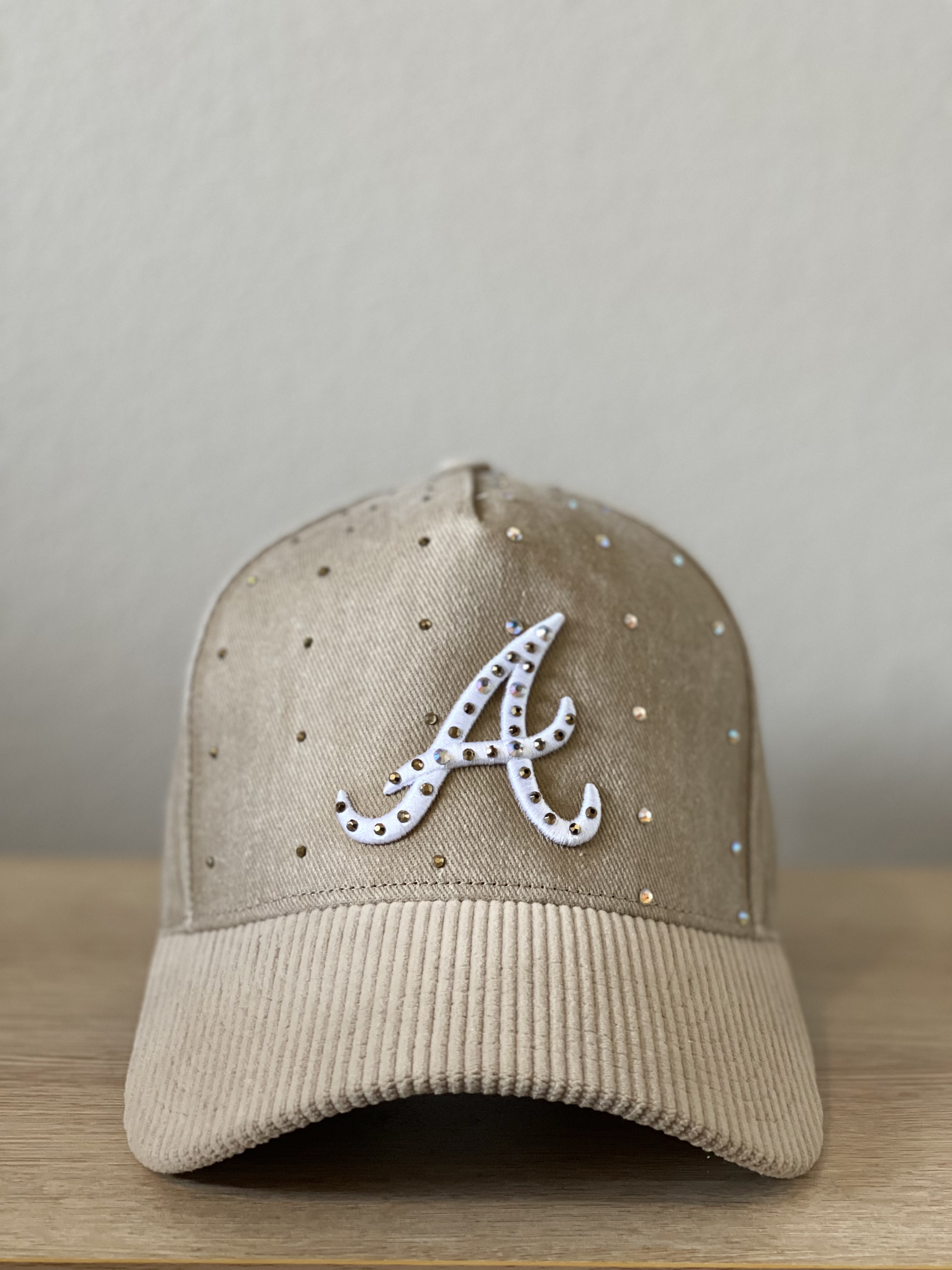 Beige Atlanta cap with crystal-studded script A and tonal scattered studs, front view.