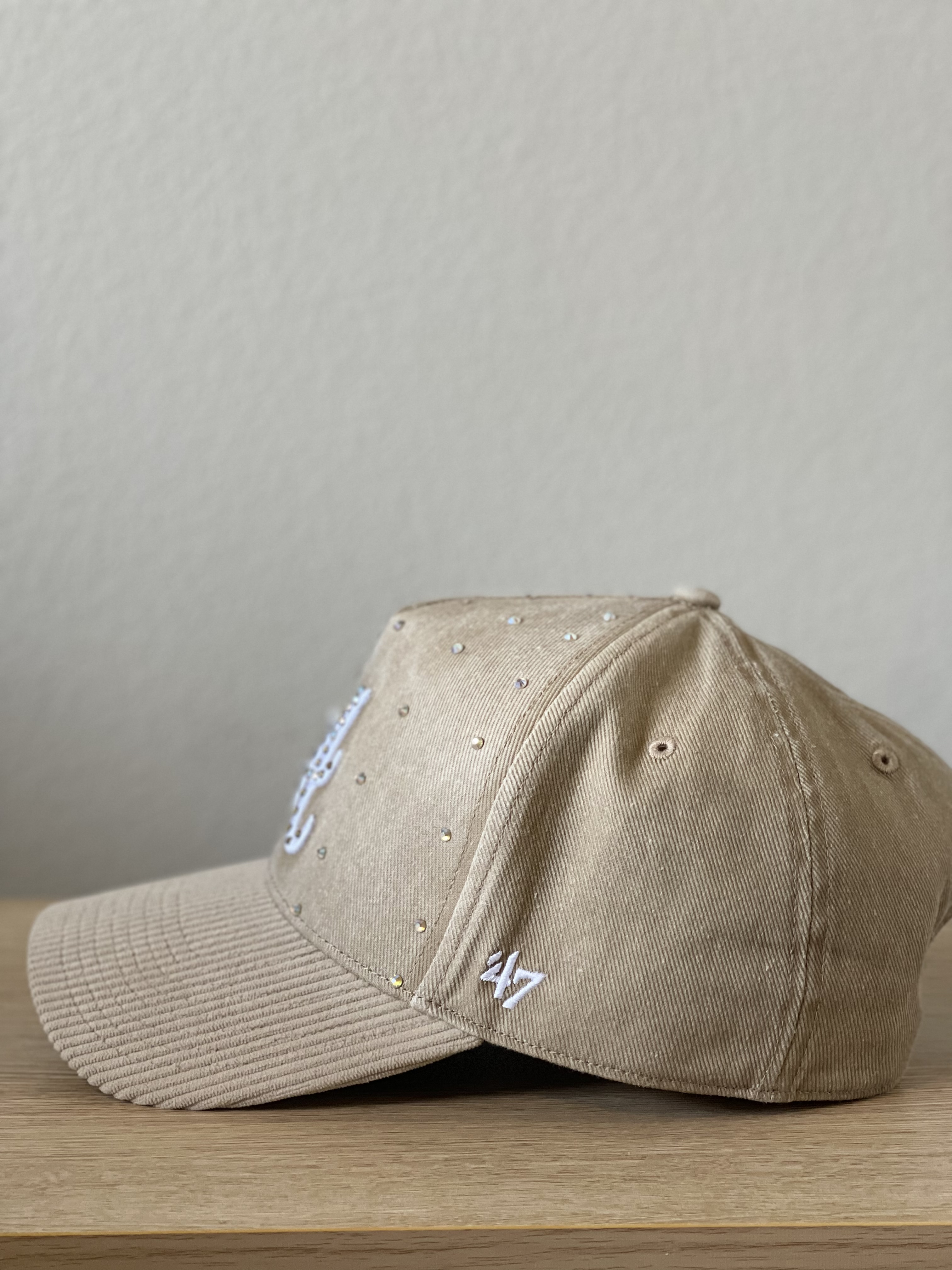 Beige Atlanta cap with crystal-studded script A and cord brim, side profile.